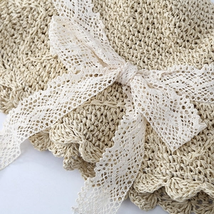 Detailed view of the intricate straw weave and elegant lace bow on a beige sun hat