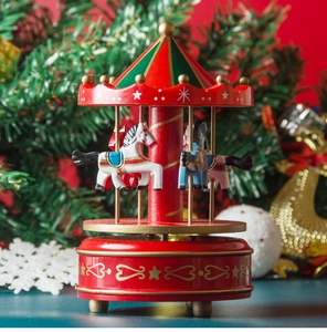 Close-up of red and gold Christmas carousel music box with horses in festive setting