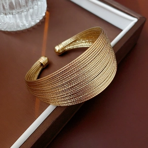 Macro shot of a layered gold-plated braided metal cuff with adjustable round bead ends