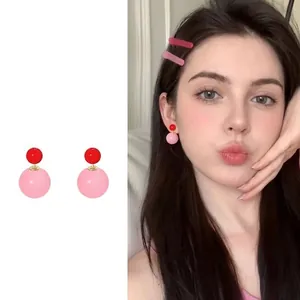 Detailansicht der Doppelkugel-Ohrstecker mit glänzenden roten und rosa Harzperlen am Modell