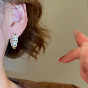 Gros plan de boucles d'oreilles C en or 18 carats avec détails en émail blanc rayé