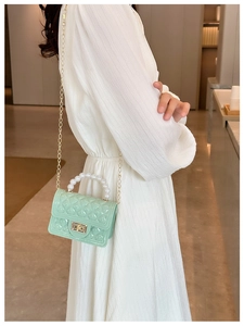 Detail of light green jelly handbag featuring a pearl handle and gold chain strap