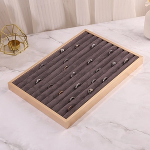 Detail view of champagne gold jewelry tray with grey velvet ring slots on marble desk