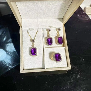 Detailed top view of a gold jewelry set with purple gemstones in a gift box