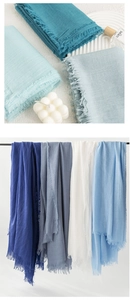 Close-up of lightweight linen scarves with frayed edges in blue and white tones