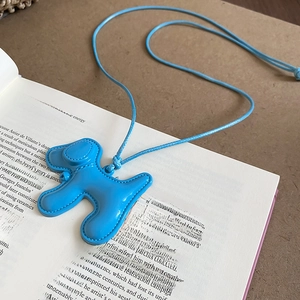 Détail du pendentif chien bleu clair avec coutures précises sur une page de livre