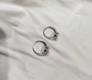 Detail of 925 silver rings with 6mm heart-shaped pink and yellow gemstones on silk