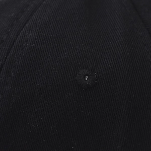 Dettaglio macro dell'occhiello ricamato sul tessuto in twill di cotone nero del berretto