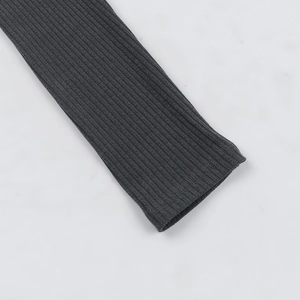 Close-up of dark grey ribbed knit fabric showing detailed texture on long-sleeved dress