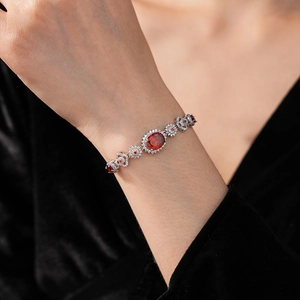 Detailed shot of a silver bracelet with oval deep red gemstone and white zircons