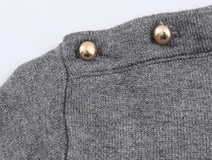 Close-up of grey knit fabric texture with two decorative golden dome metal buttons
