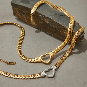 Detailed close-up of gold and silver heart necklaces on a textured dark stone background