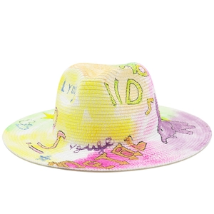 Detail view of woven straw sun hat featuring colorful graffiti and hand-painted art