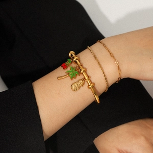 Dettaglio di bracciali placcati oro 18k con ciondoli a ciliegia, cocco e ananas