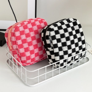 Close-up of pink and black checkered knit pouches inside a white metal storage basket