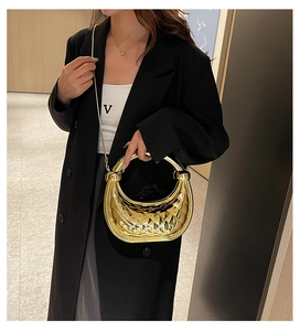 Close-up of golden crescent hobo bag with quilted metal texture and ring handle