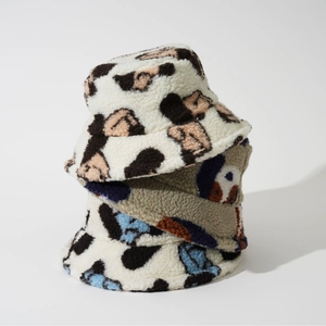 Detailed stack of three plush faux lamb wool bucket hats with cow print and patterns
