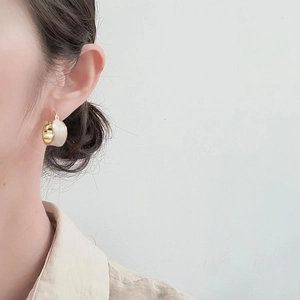 18K gold plated hoop earrings with white enamel finish shown on a model's ear