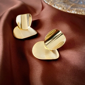 Detailed view of gold geometric stud earrings with matte and polished layering