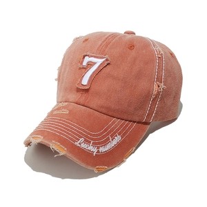 Detail showing vintage distressed orange baseball cap with white number 7 embroidery