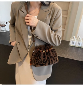 Detail of leopard print faux fur bucket bag with amber beaded handle and leather strap