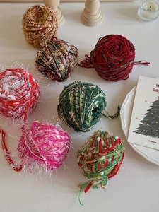Close-up of DIY Christmas yarn balls with gold threads for festive tree decorations