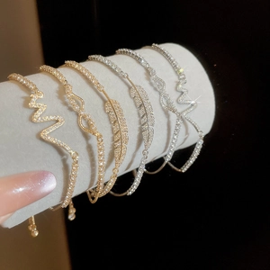 Macro shot of cubic zirconia feather bracelets in gold and silver on a velvet display
