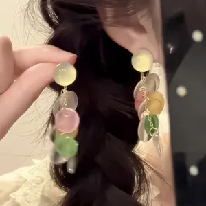 Macro shot of colorful layered resin circle drop earrings on model with gold plating