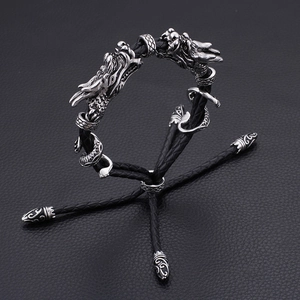 Vue détaillée des têtes de dragon en métal argenté sur un bracelet en cuir tressé noir