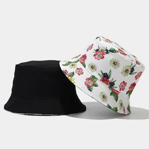 Detail of a floral print cotton bucket hat paired with a minimalist solid black outdoor cap