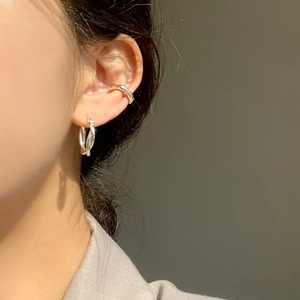 Macro shot of silver woven knot earrings and minimalist ear cuff worn by a female model