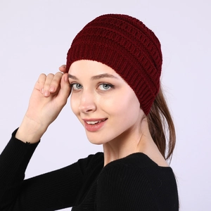 Detail view of burgundy knitted headband with ponytail hole for women in winter