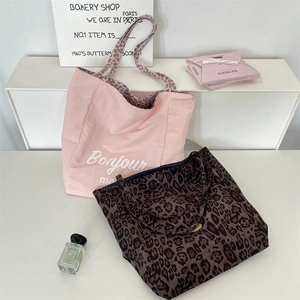Detail of pink floral and leopard print tote bags with Bonjour ma text on minimalist surface