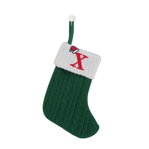 Detail of green knitted Christmas stocking with white cuff and red embroidered letter X