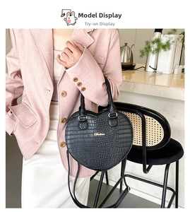 Détail d'un sac à main noir en forme de cœur avec texture crocodile et finitions dorées