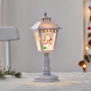 Illuminated Christmas snow globe lantern with snowman and glitter on a snowy base