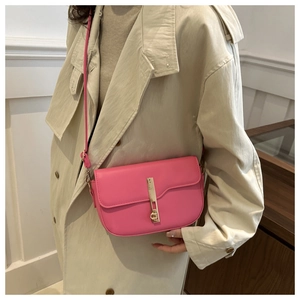Detailed view of pink leather saddle bag with gold buckle on beige trench coat