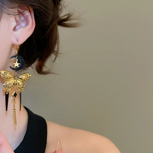 Gros plan de boucles d'oreilles vintage lune et papillon avec pompons portées par un mannequin