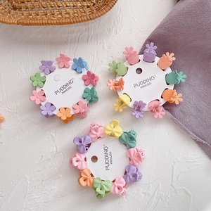 Close-up of candy-colored mini flower and bow hair claws for kids on white surface