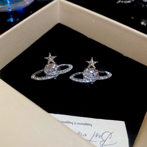 Macro shot of sparkling silver saturn stud earrings with diamonds on black velvet
