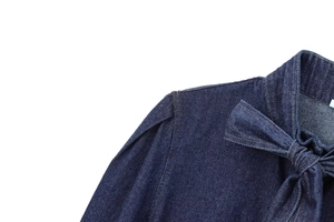 Detailed macro view of dark blue denim shirt featuring bow-tie collar and reinforced seams