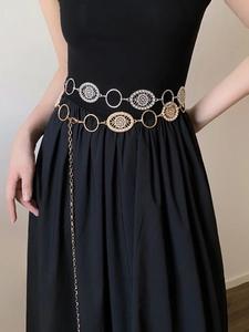 Detail of vintage silver and gold metal waist chains with pearls on a black skirt