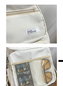 Detail of white backpack featuring mesh front pocket and branded fashion label