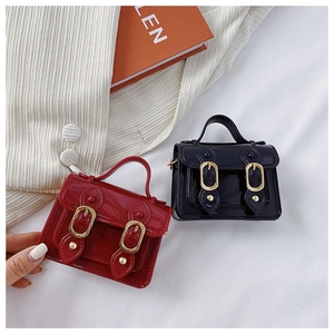 Close-up of mini patent leather Cambridge bags in burgundy and black with gold buckles