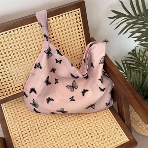 Pink lace tote bag with black butterfly prints displayed on a vintage rattan chair