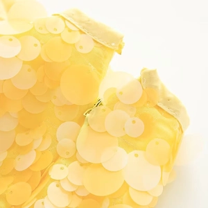 Detail shot of yellow overlapping sequins and invisible zipper on a stylish mini skirt
