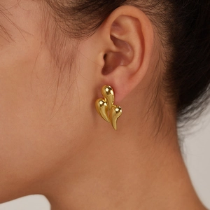 Close-up of a model wearing a gold teardrop earring with a sleek streamlined metal design