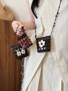 Detail of bohemian coconut shell cross-body bag with ethnic floral accents and woven strap