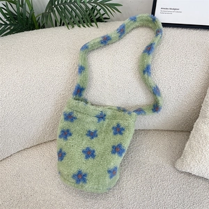 Close-up of plush faux shearling bucket bag with blue floral patterns on a sofa