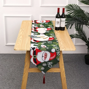 Close-up of knitted Christmas table runner with Santa patterns and red pompom tassels